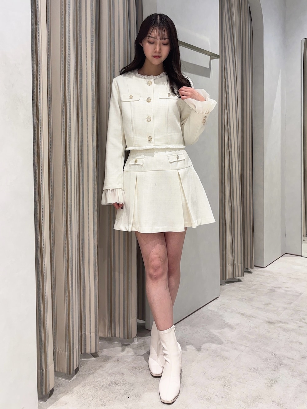 ホワイト系のノーカラージャケット、ホワイト系のスカート、ホワイト系のブーツを着用したレディースの春コーディネートの3枚目の写真