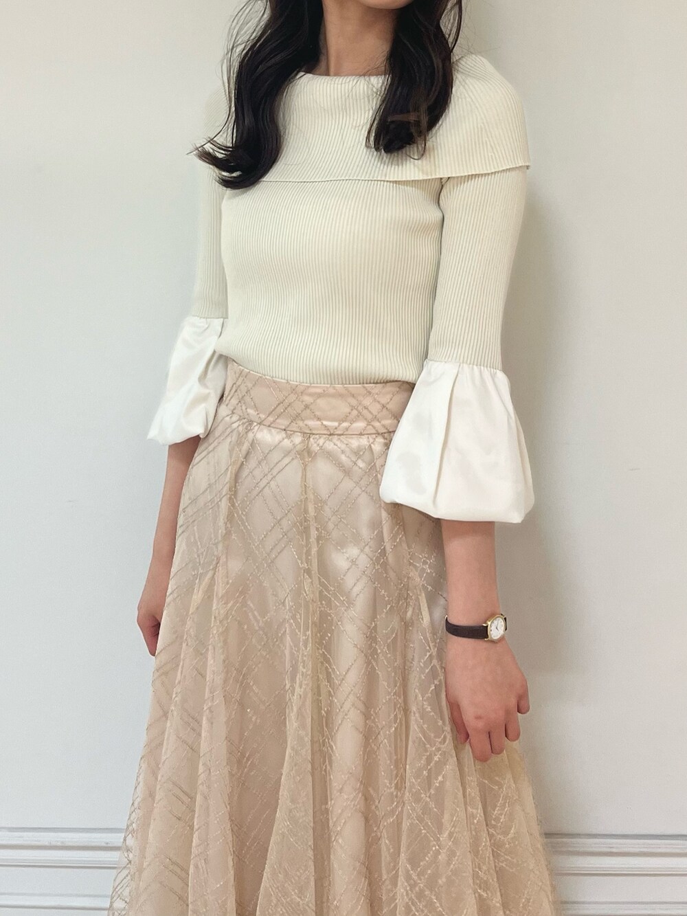 ベージュ系のスカート、ゴールド系のパンプス、ホワイト系のニット/セーターを着用したレディースの春コーディネートの4枚目の写真