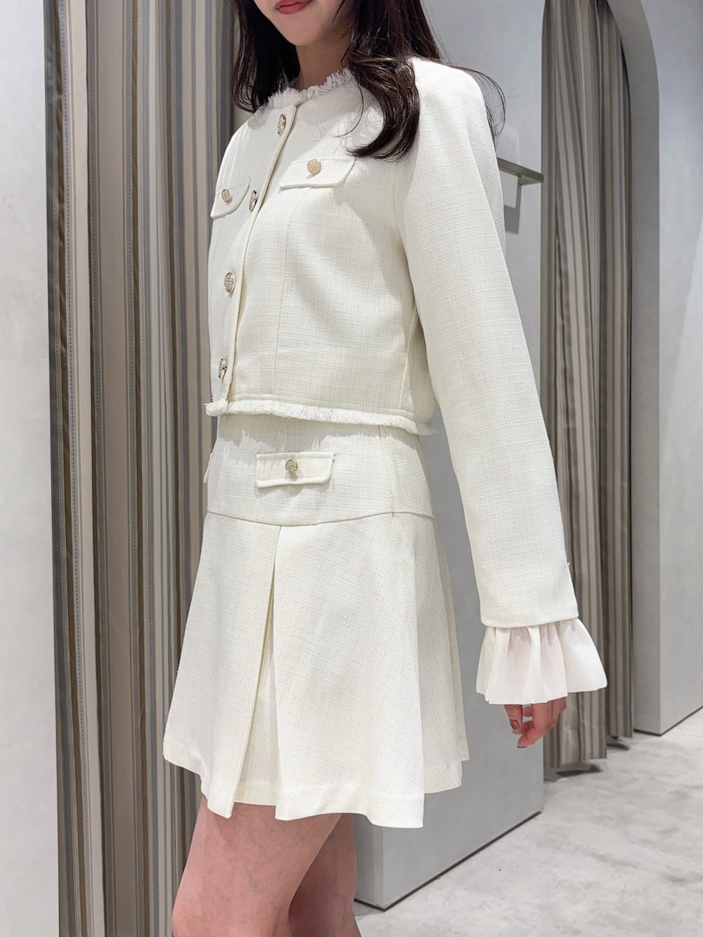 ホワイト系のノーカラージャケット、ホワイト系のスカート、ホワイト系のブーツを着用したレディースの春コーディネートの8枚目の写真