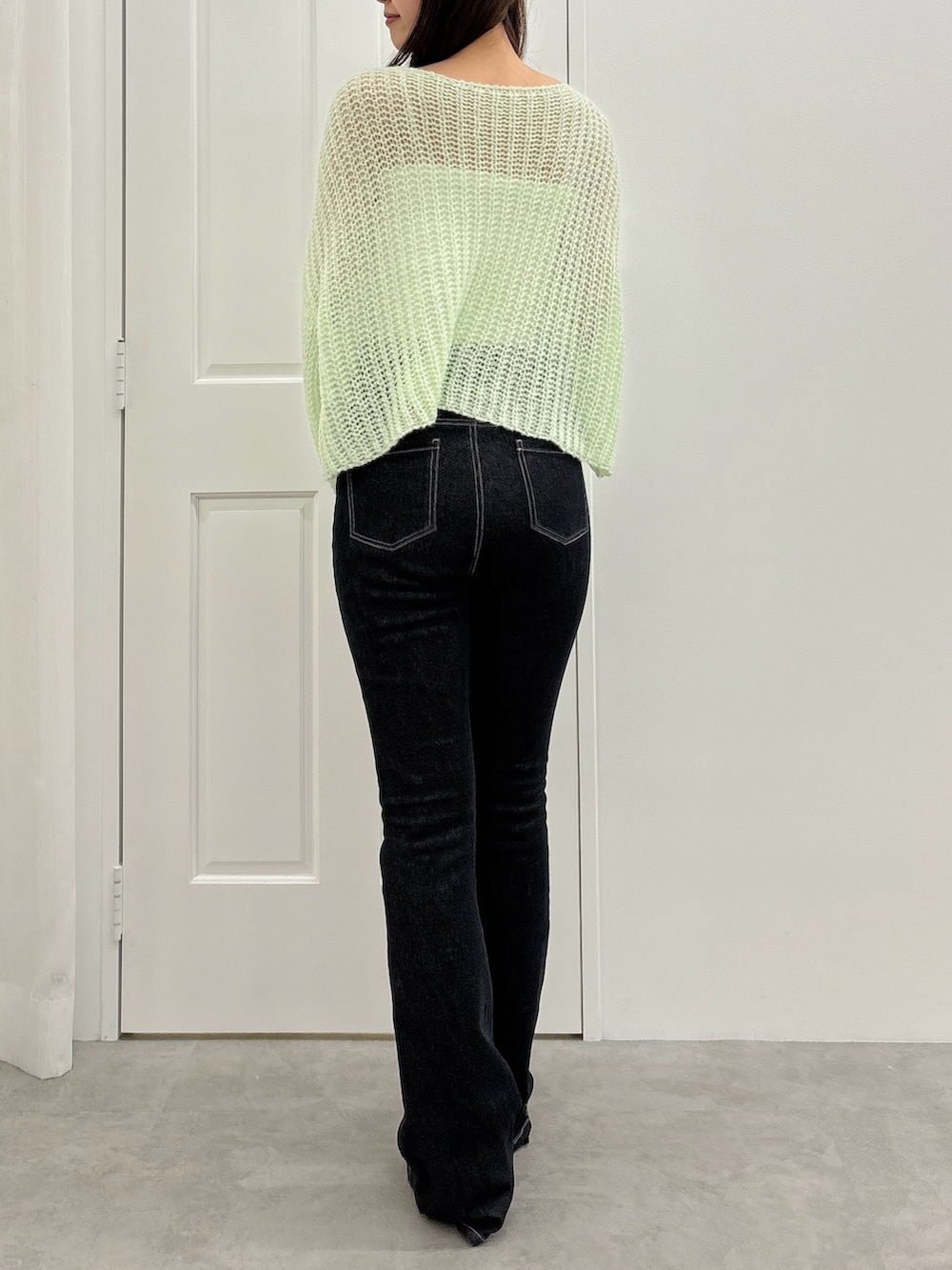 ブラック系のデニムパンツ、グリーン系のニット/セーター、ブラック系のパンプスを着用したレディースの夏コーディネートの3枚目の写真