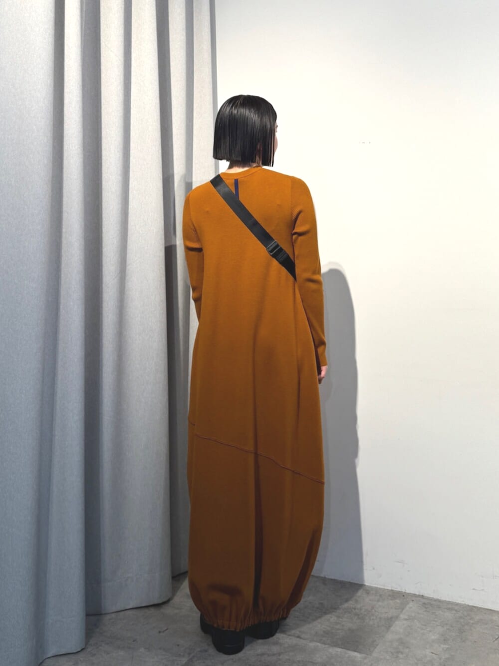 イエロー系のワンピース、ブラック系のショルダーバッグを着用したレディースの秋コーディネートの2枚目の写真