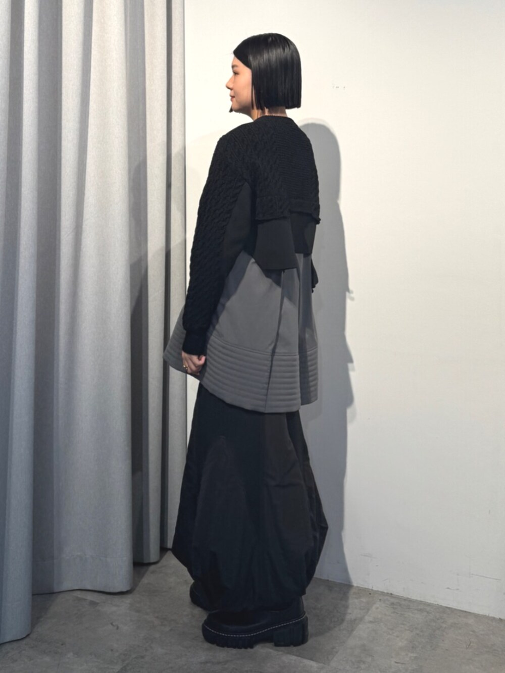ブラック系のニット/セーター、ブラック系のスカート、グレー系のシャツ/ブラウスを着用したレディースの秋コーディネートの2枚目の写真