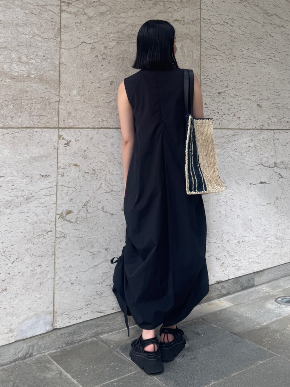 ブラック系のサンダル、ブラック系のワンピース、ブルー系のトートバッグを着用したレディースの夏コーディネートの3枚目の写真