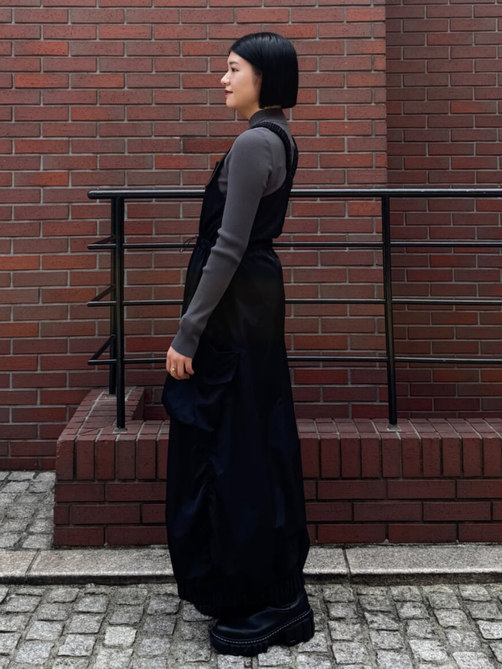 グレー系のニット/セーター、ブラック系のワンピースを着用したレディースの秋コーディネートの2枚目の写真