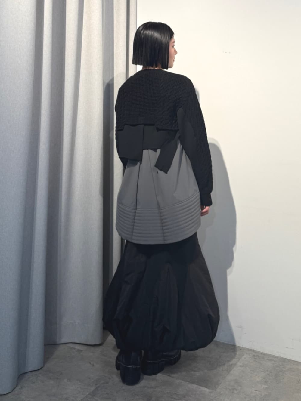 ブラック系のニット/セーター、ブラック系のスカート、グレー系のシャツ/ブラウスを着用したレディースの秋コーディネートの3枚目の写真