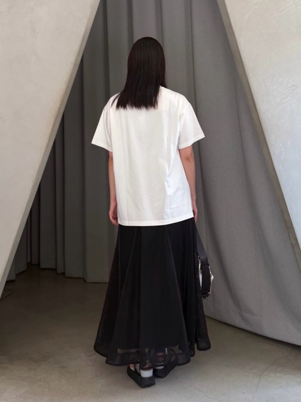 シルバー系のショルダーバッグ、ホワイト系のTシャツ/カットソー、ブラック系のスカートを着用したレディースの夏コーディネートの3枚目の写真