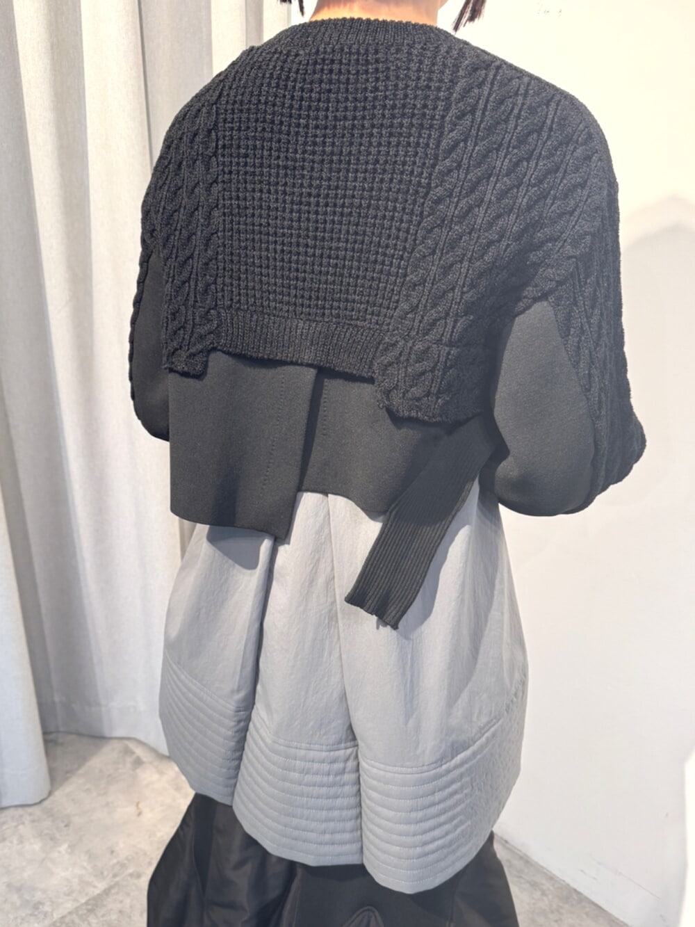 ブラック系のニット/セーター、ブラック系のスカート、グレー系のシャツ/ブラウスを着用したレディースの秋コーディネートの6枚目の写真