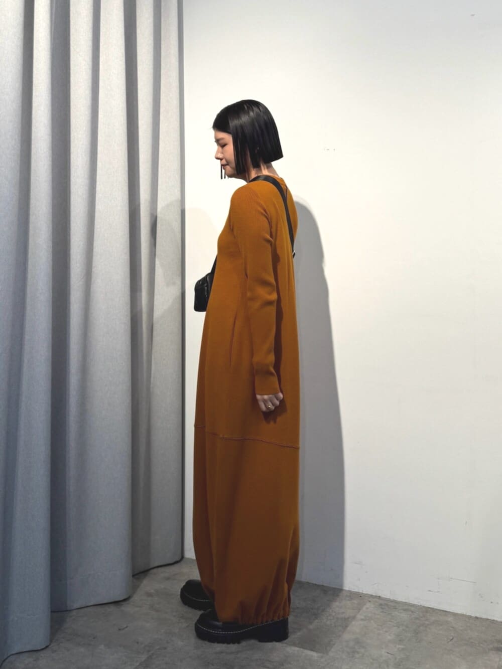 イエロー系のワンピース、ブラック系のショルダーバッグを着用したレディースの秋コーディネートの3枚目の写真