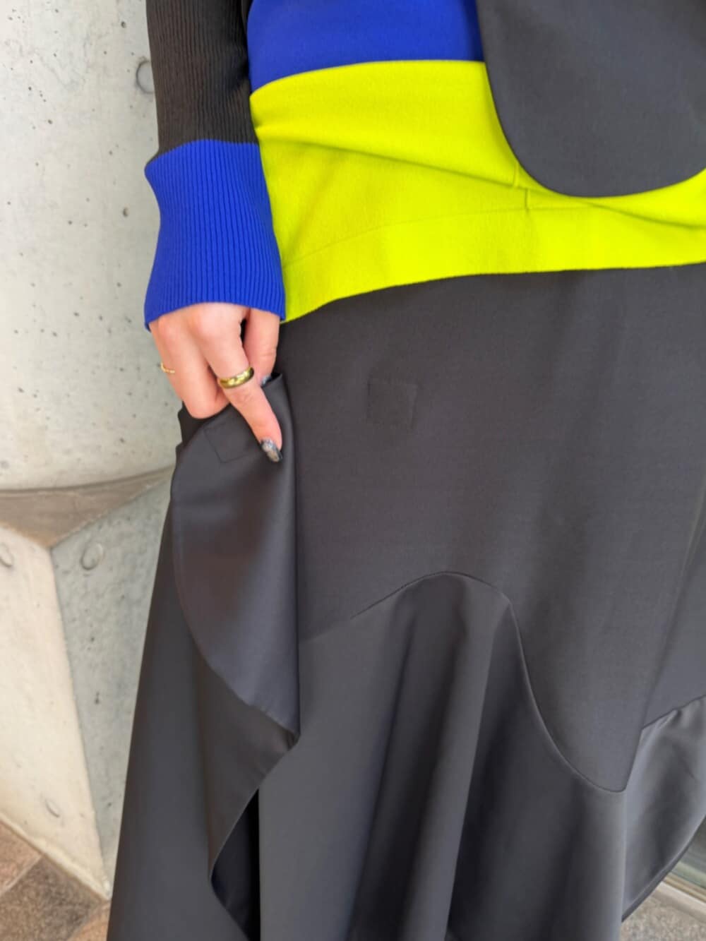 ブラック系のベスト、グリーン系のニット/セーター、ブラック系のスカートを着用したレディースの秋コーディネートの6枚目の写真