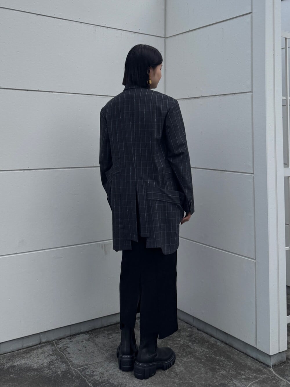 ブラック系のブーツ、グレー系のテーラードジャケット、ブラック系のワンピースを着用したレディースの秋コーディネートの3枚目の写真