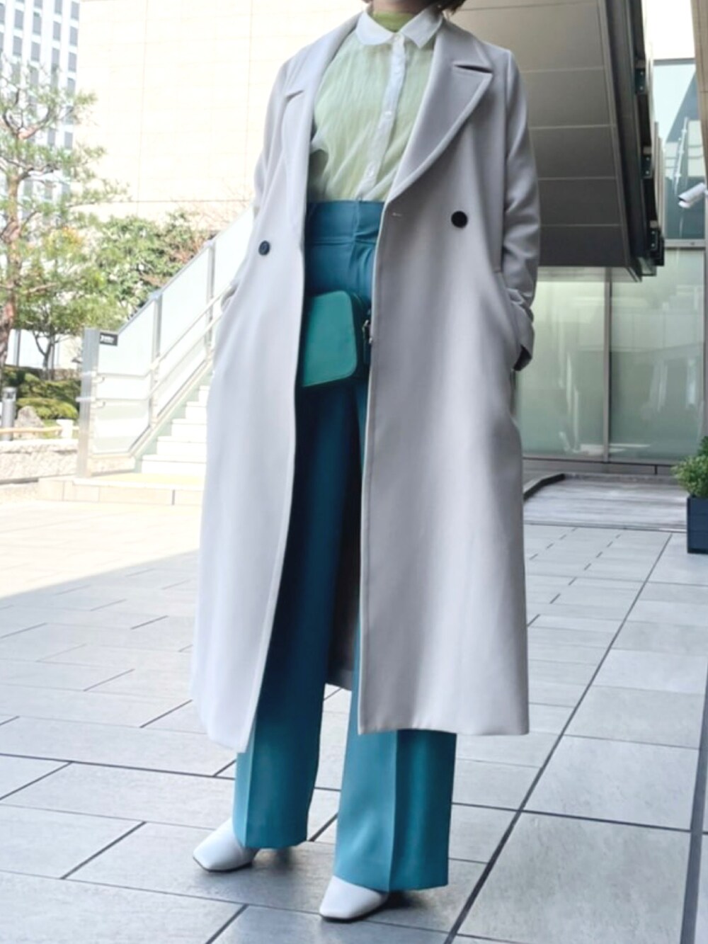 グリーン系のショルダーバッグ、グリーン系のTシャツ/カットソー、ホワイト系のチェスターコートを着用したレディースの春コーディネートの2枚目の写真