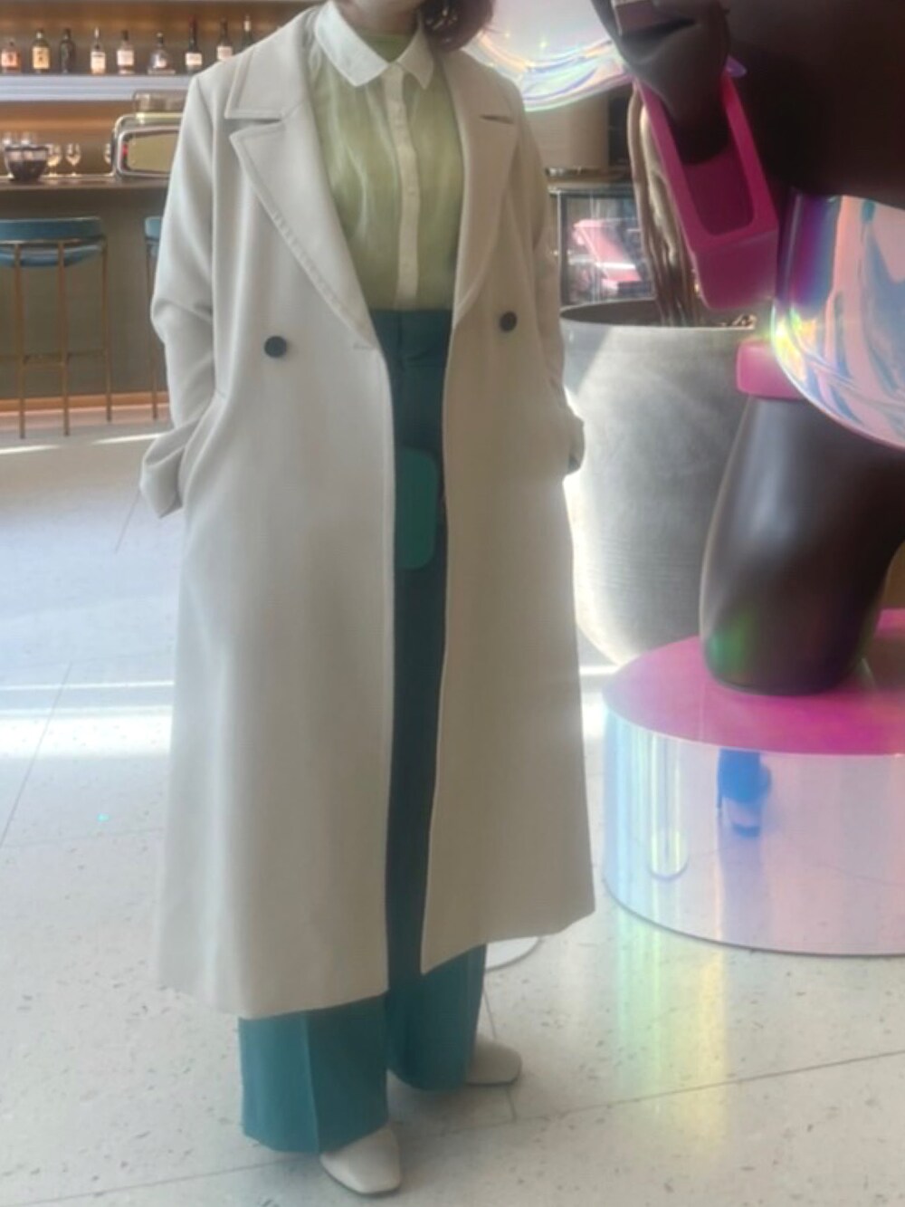 グリーン系のショルダーバッグ、グリーン系のTシャツ/カットソー、ホワイト系のチェスターコートを着用したレディースの春コーディネートの3枚目の写真