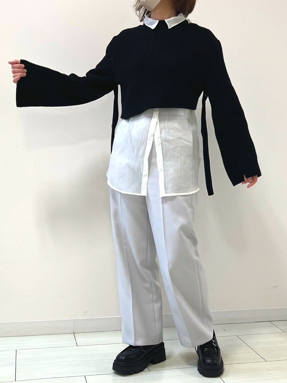 ブラック系のニット/セーター、ホワイト系のシャツ/ブラウス、ホワイト系のスラックスを着用したレディースの春コーディネートの2枚目の写真