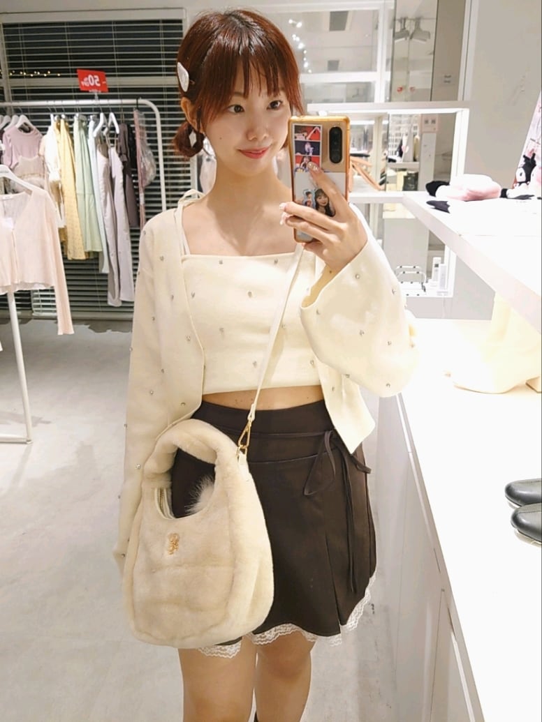 ホワイト系のカーディガン/ボレロ、ホワイト系のキャミソール、ブラウン系のスカートを着用したレディースの秋コーディネートの2枚目の写真