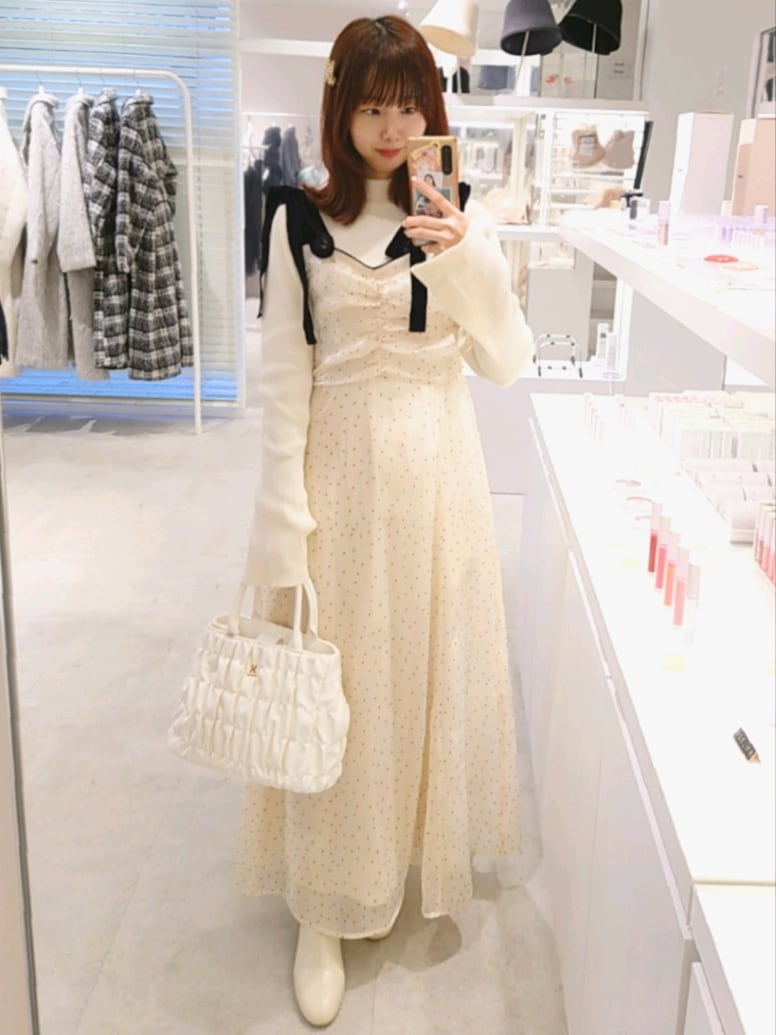 ホワイト系のブーツ、ホワイト系のハンドバッグ、ホワイト系のムートンコートを着用したレディースの冬コーディネートの2枚目の写真