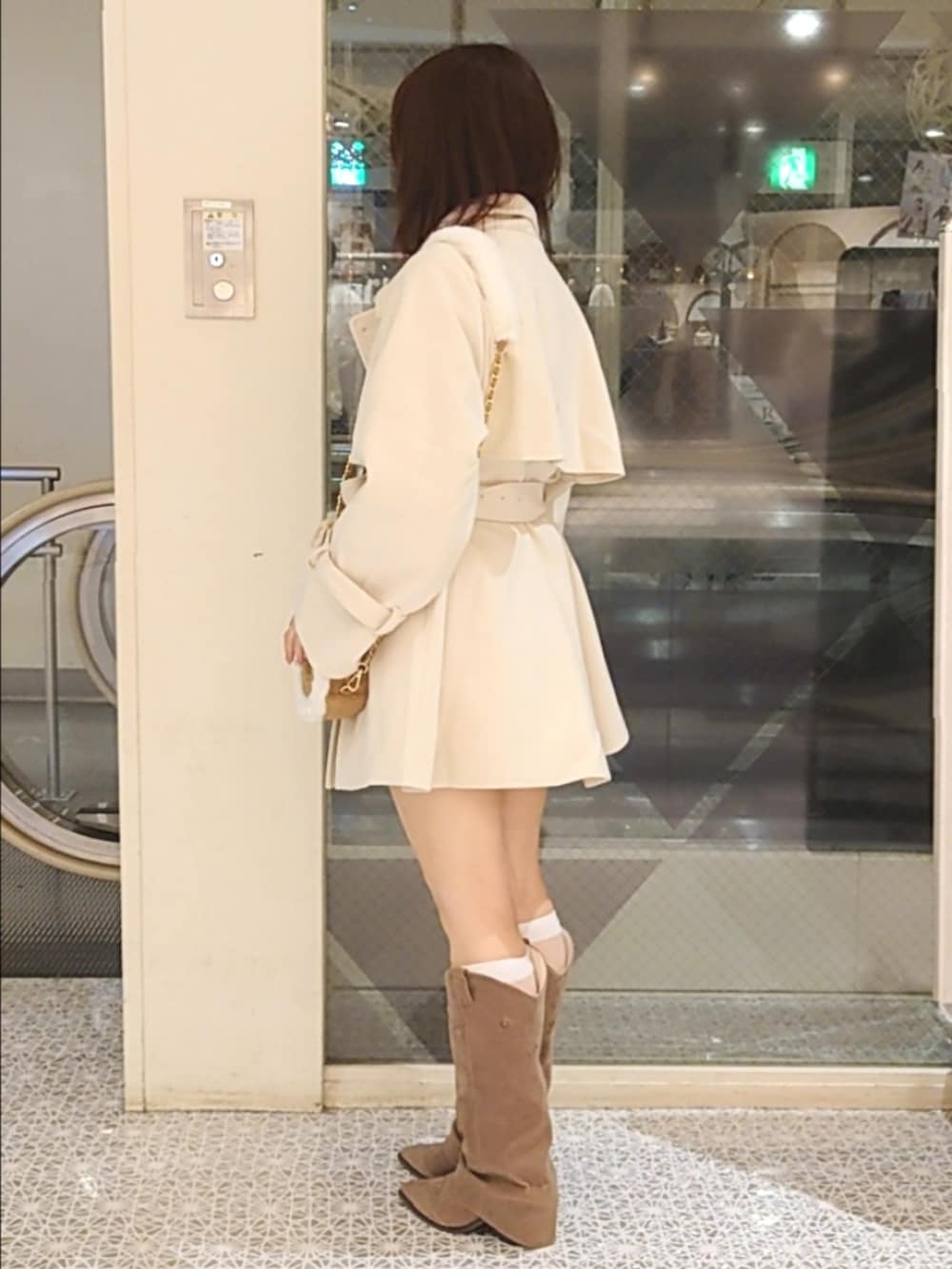 ホワイト系のチェスターコート、ベージュ系のショルダーバッグ、ベージュ系のブーツを着用したレディースの秋コーディネートの3枚目の写真