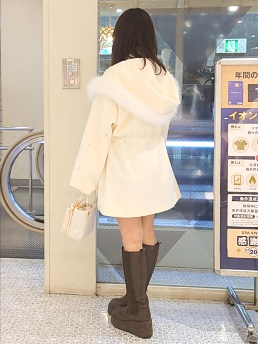 ホワイト系のノーカラーコート、ホワイト系のニット/セーター、ホワイト系のショルダーバッグを着用したレディースの冬コーディネートの3枚目の写真