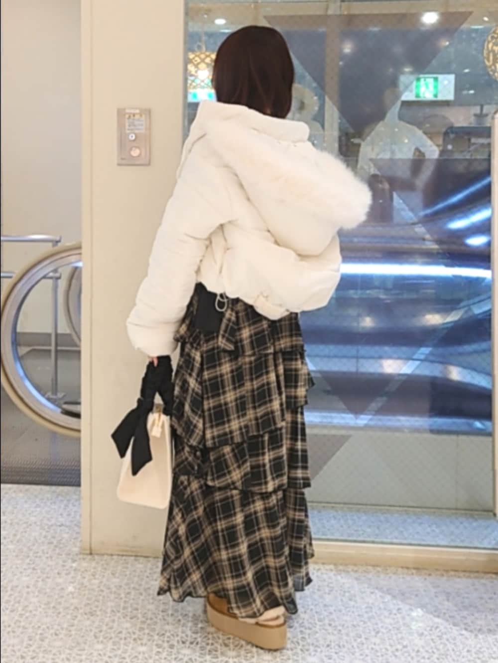 ホワイト系のダウンジャケット/コート、ブルー系のニット/セーター、ブラック系のスカートを着用したレディースの秋コーディネートの3枚目の写真