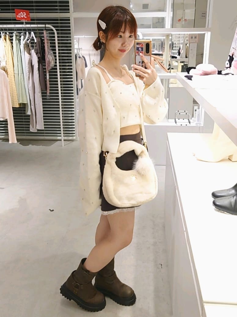 ホワイト系のカーディガン/ボレロ、ホワイト系のキャミソール、ブラウン系のスカートを着用したレディースの秋コーディネートの3枚目の写真