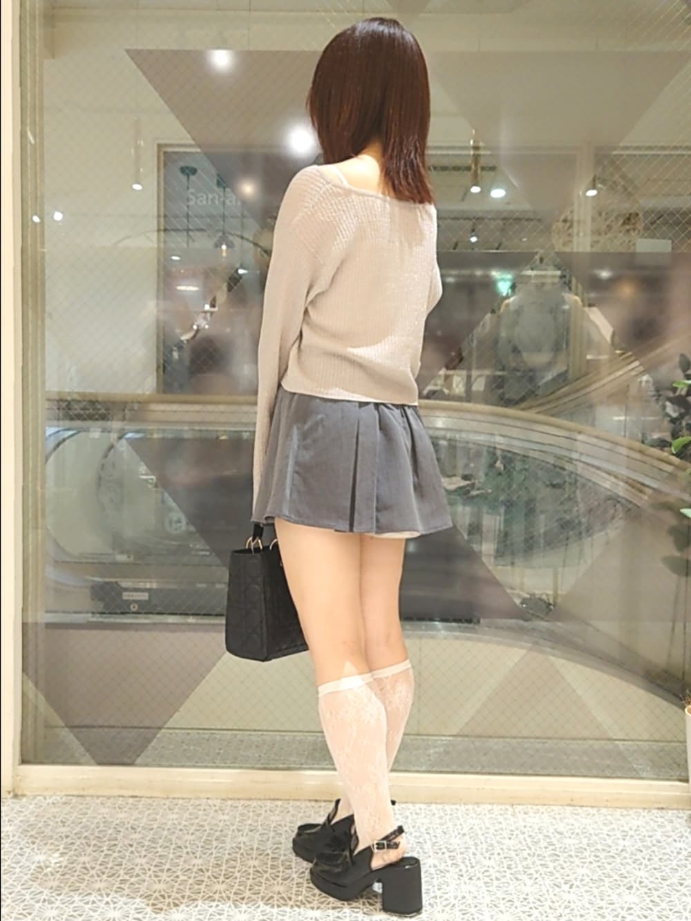 ピンク系のカーディガン/ボレロ、ホワイト系のキャミソール、グレー系のスカートを着用したレディースの秋コーディネートの3枚目の写真