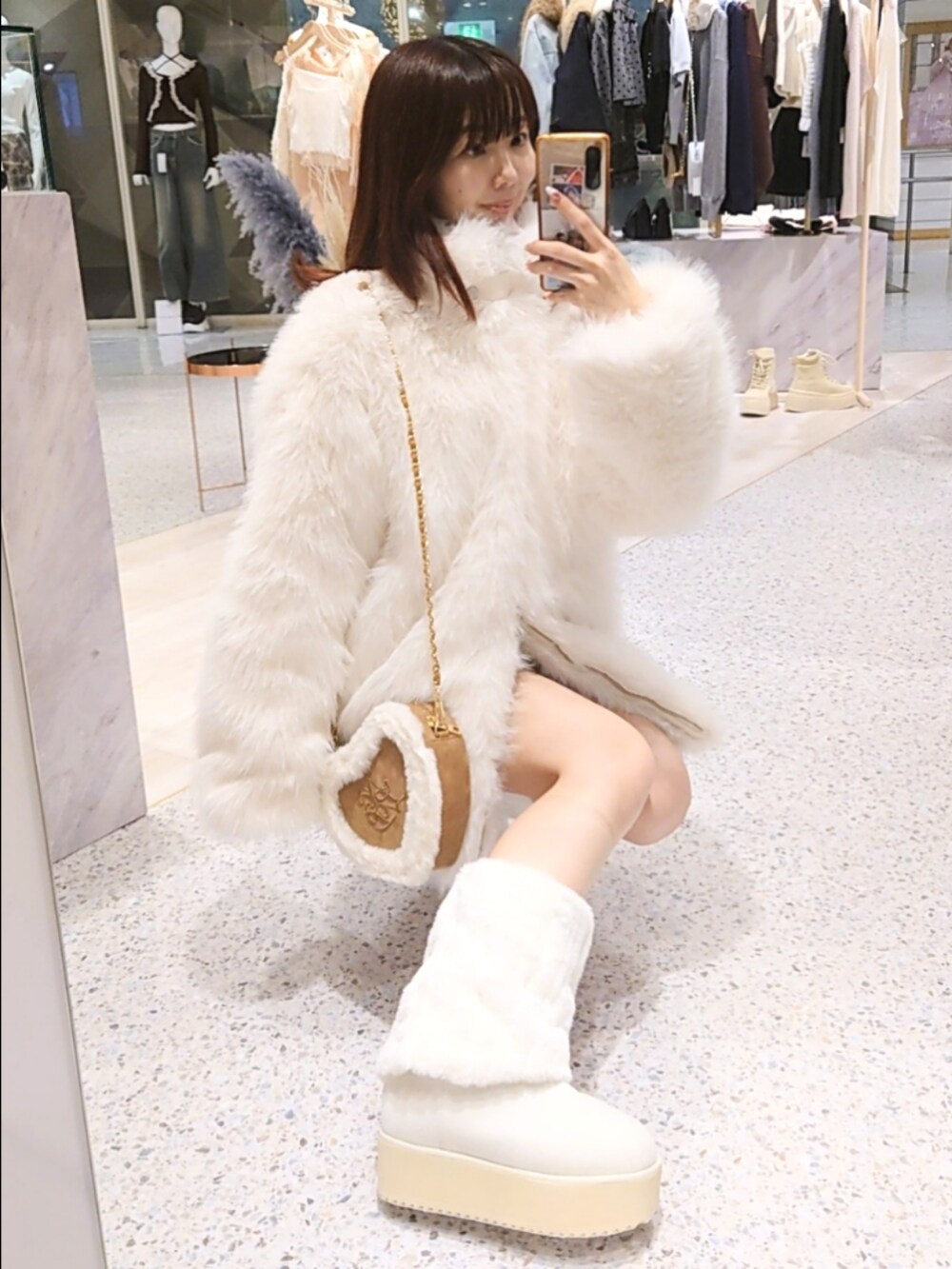 ホワイト系のその他アウター、ベージュ系のショルダーバッグ、ホワイト系のブーツを着用したレディースの秋コーディネートの2枚目の写真