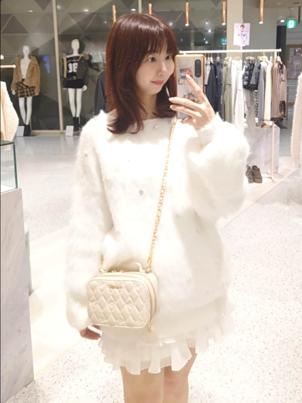 ホワイト系のニット/セーター、ピンク系のショルダーバッグ、ホワイト系のスカートを着用したレディースの秋コーディネートの2枚目の写真