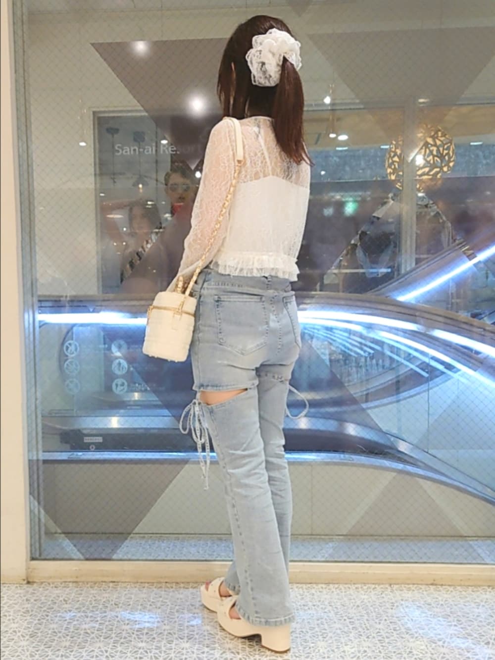 ホワイト系のカーディガン/ボレロ、ホワイト系のキャミソール、ブルー系のデニムパンツを着用したレディースの夏コーディネートの3枚目の写真