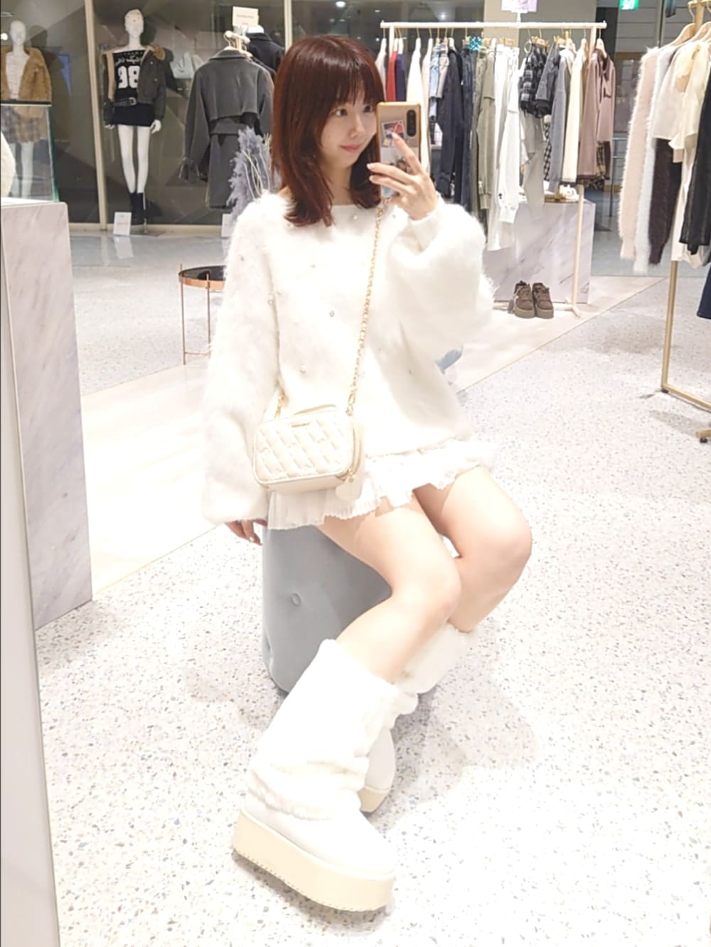 ホワイト系のニット/セーター、ピンク系のショルダーバッグ、ホワイト系のスカートを着用したレディースの秋コーディネートの3枚目の写真