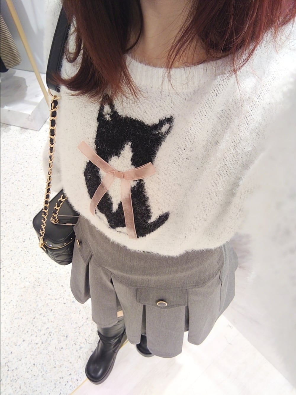 ホワイト系のニット/セーター、グレー系のスカート、ブラック系のショルダーバッグを着用したレディースの冬コーディネートの2枚目の写真