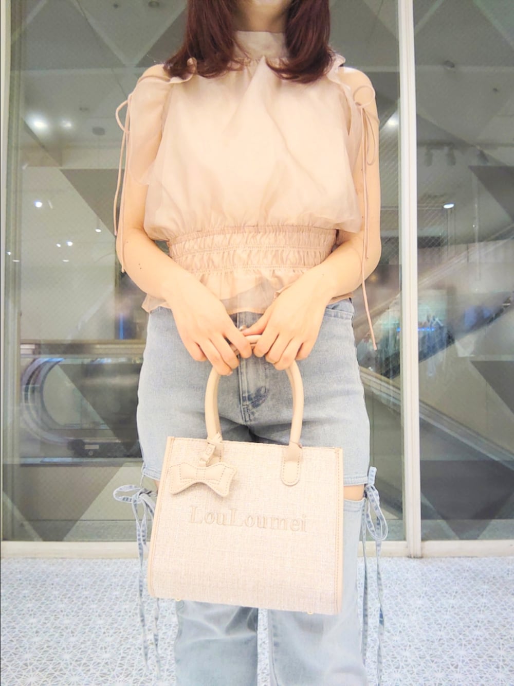 ベージュ系のシャツ/ブラウス、ブルー系のデニムパンツ、ベージュ系のトートバッグを着用したレディースの夏コーディネートの3枚目の写真