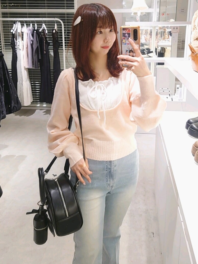 ピンク系のニット/セーター、ブルー系のデニムパンツ、ブラック系のハンドバッグを着用したレディースの冬コーディネートの2枚目の写真