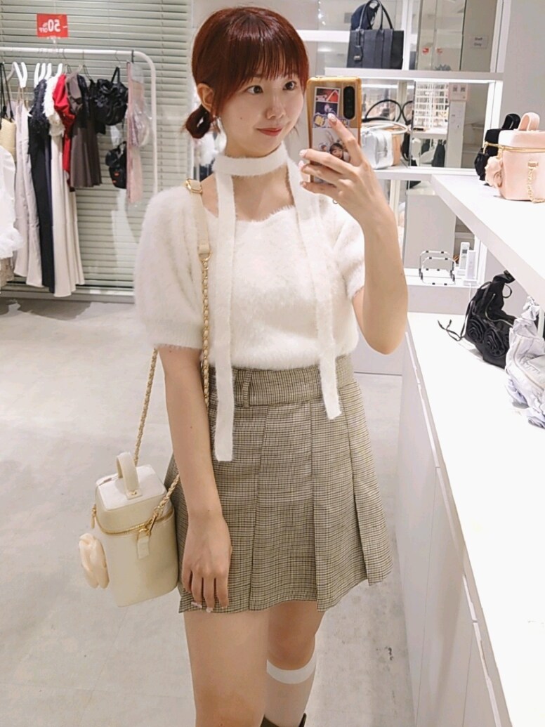 ホワイト系のニット/セーター、ベージュ系のスカート、ブラウン系のブーツを着用したレディースの夏コーディネートの2枚目の写真