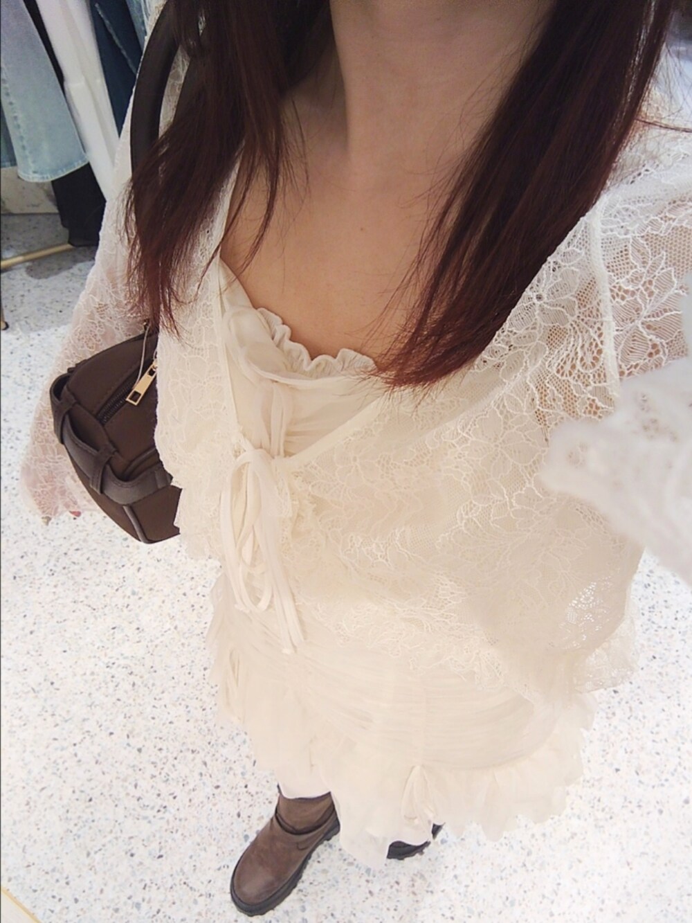 ホワイト系のチュニック、ホワイト系のカーディガン/ボレロ、ブラウン系のショルダーバッグを着用したレディースの夏コーディネートの3枚目の写真