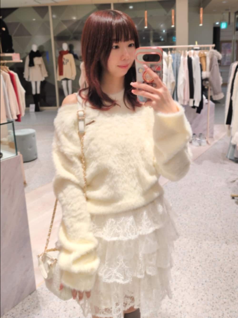 イエロー系のニット/セーター、ホワイト系のショルダーバッグ、ホワイト系のスカートを着用したレディースの冬コーディネートの2枚目の写真