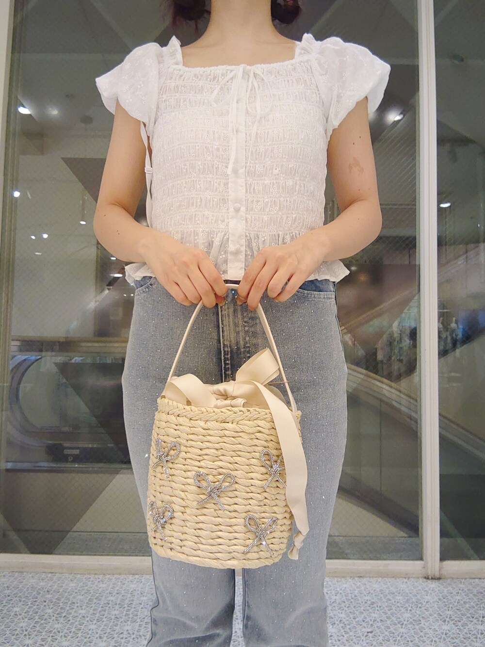 ホワイト系のシャツ/ブラウス、ブルー系のデニムパンツ、ホワイト系のかごバッグを着用したレディースの夏コーディネートの2枚目の写真