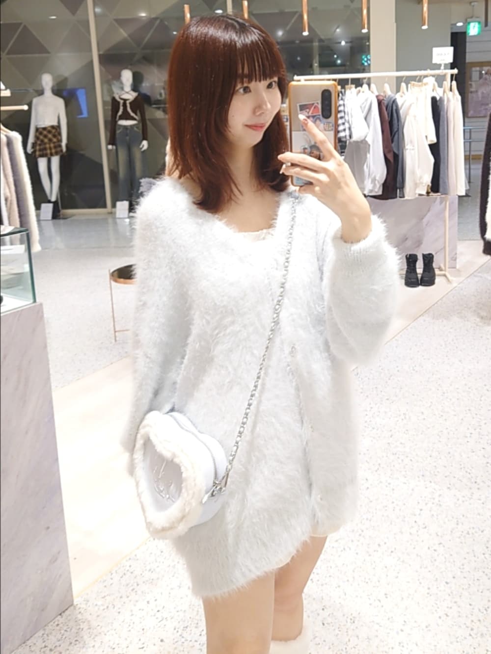 ブルー系のカーディガン/ボレロ、ホワイト系のキャミソール、ブルー系のショルダーバッグを着用したレディースの秋コーディネートの2枚目の写真