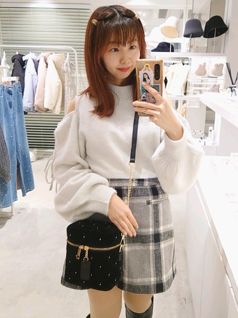 グレー系のニット/セーター、グレー系のスカート、ブラック系のショルダーバッグを着用したレディースの冬コーディネートの2枚目の写真