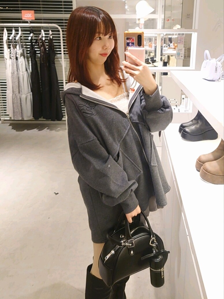 グレー系のパーカー、ホワイト系のキャミソール、グレー系のスカートを着用したレディースの冬コーディネートの2枚目の写真