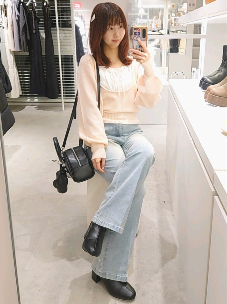 ピンク系のニット/セーター、ブルー系のデニムパンツ、ブラック系のハンドバッグを着用したレディースの冬コーディネートの4枚目の写真