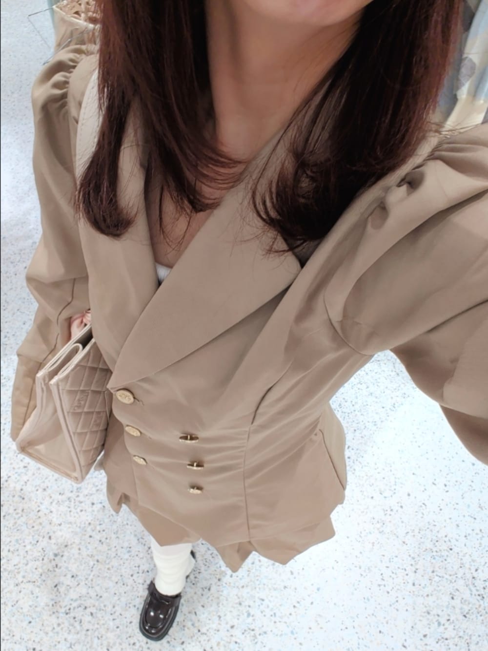 ベージュ系のテーラードジャケット、ベージュ系のスカート、ピンク系のトートバッグを着用したレディースの冬コーディネートの2枚目の写真