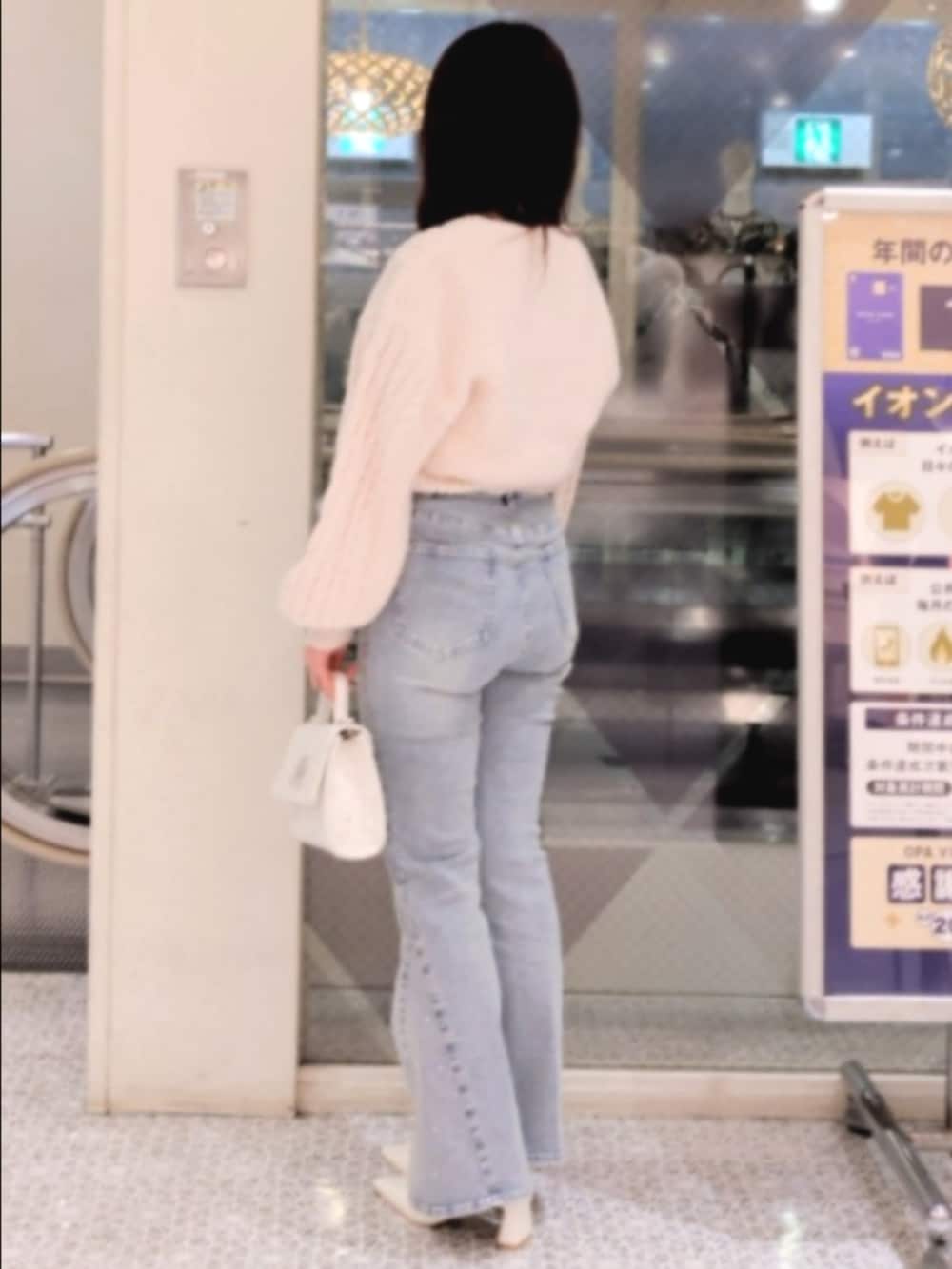 ピンク系のアンサンブル、ブルー系のデニムパンツ、ホワイト系のショルダーバッグを着用したレディースの冬コーディネートの3枚目の写真