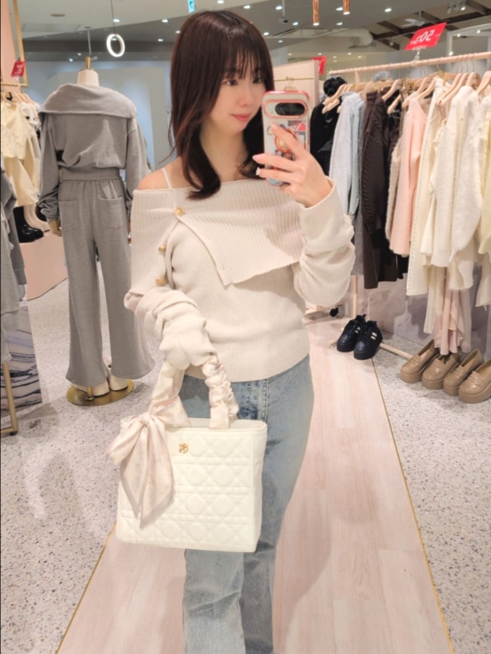 ホワイト系のニット/セーター、ブルー系のデニムパンツ、ホワイト系のトートバッグを着用したレディースの冬コーディネートの2枚目の写真