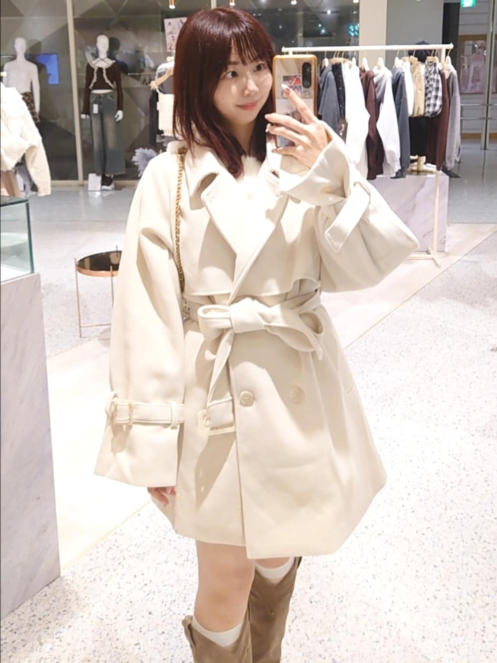 ホワイト系のチェスターコート、ベージュ系のショルダーバッグ、ベージュ系のブーツを着用したレディースの秋コーディネートの2枚目の写真