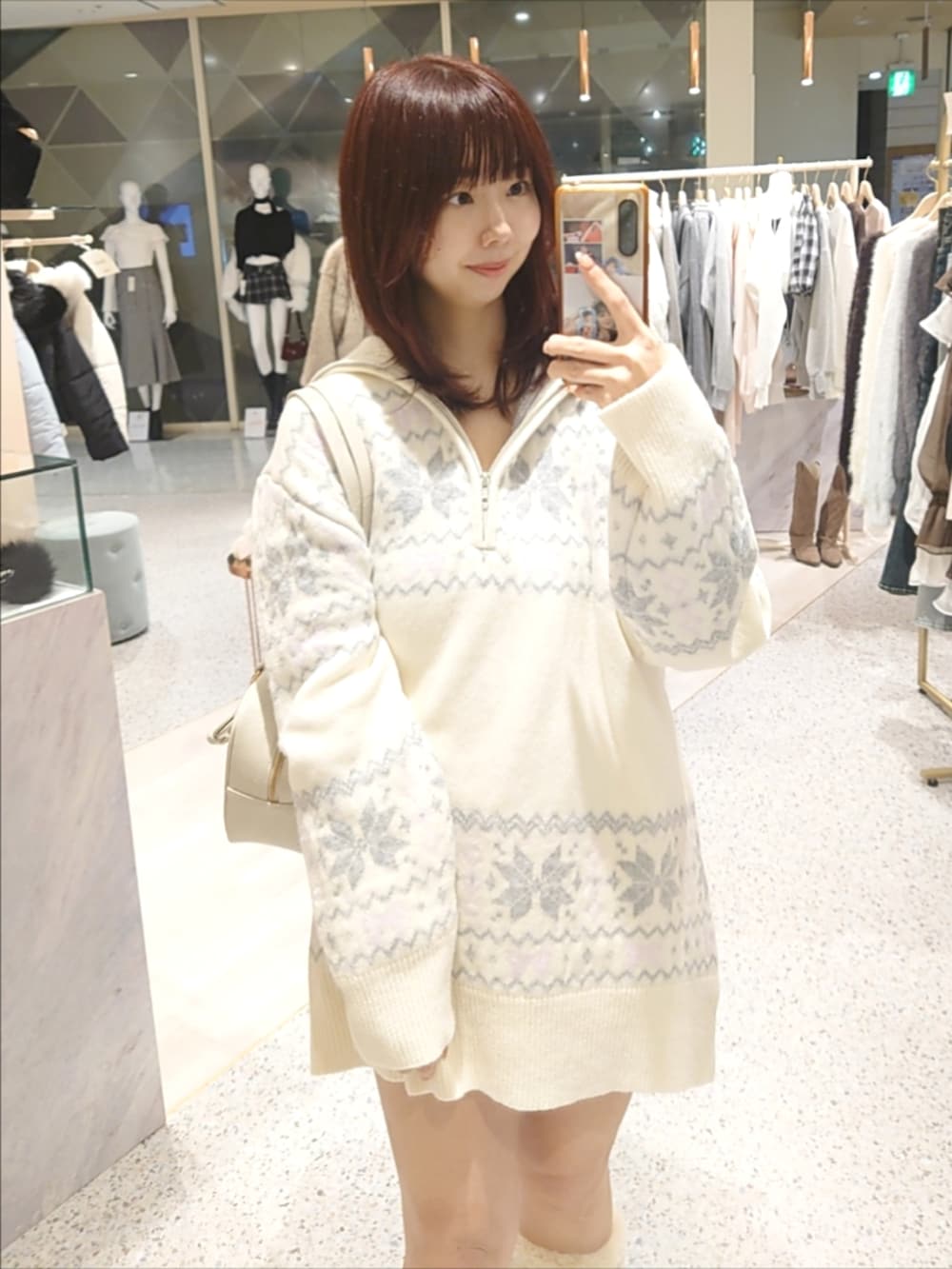 ホワイト系のニット/セーター、ホワイト系のボストンバッグ、ベージュ系のブーツを着用したレディースの冬コーディネートの2枚目の写真