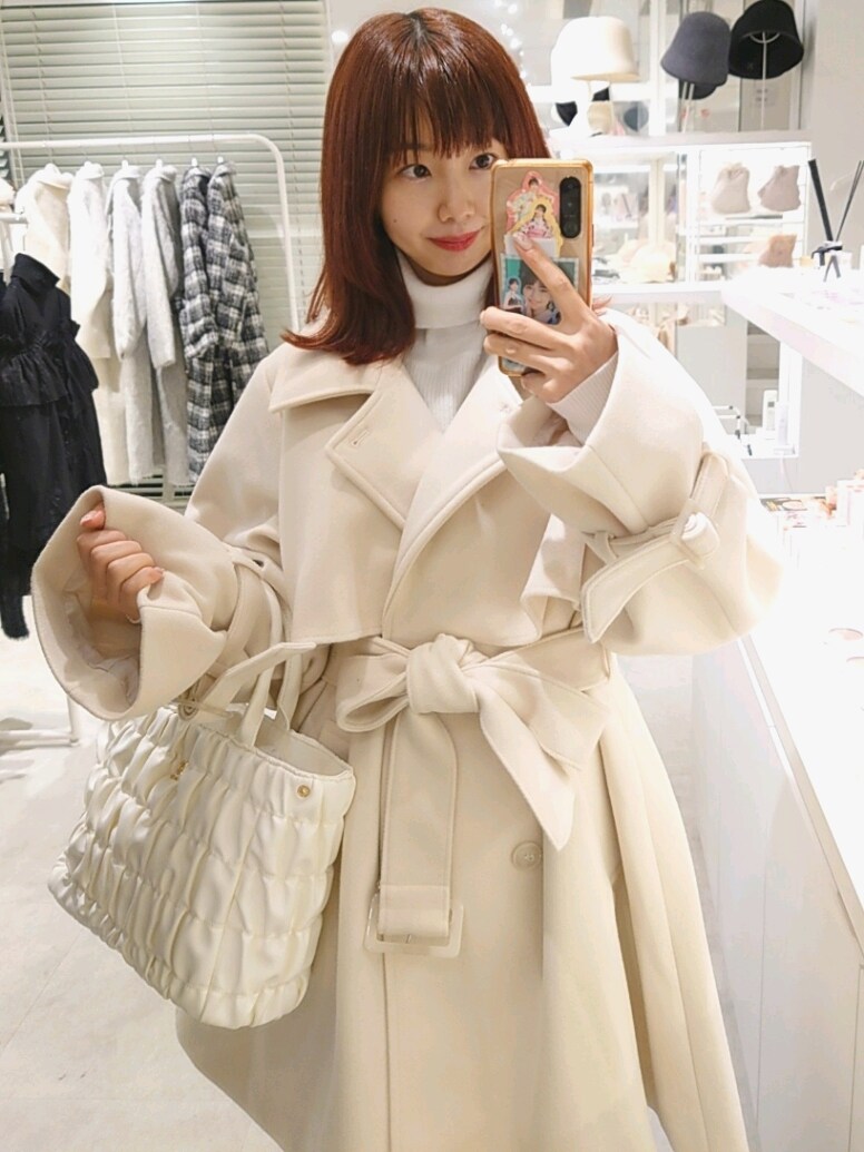 ホワイト系のピーコート、ブラック系のブーツ、ホワイト系のニット/セーターを着用したレディースの冬コーディネートの2枚目の写真