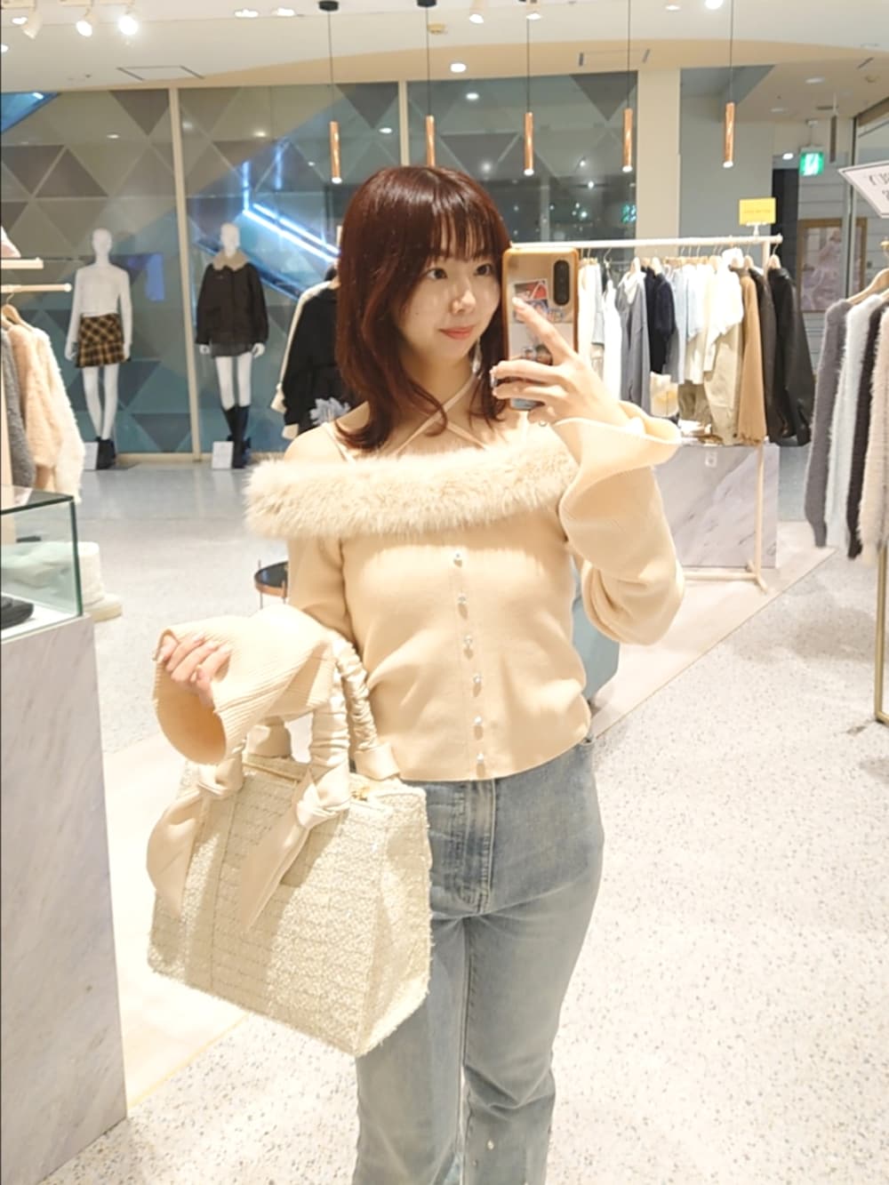 ピンク系のニット/セーター、ブルー系のデニムパンツ、ホワイト系のトートバッグを着用したレディースの秋コーディネートの2枚目の写真