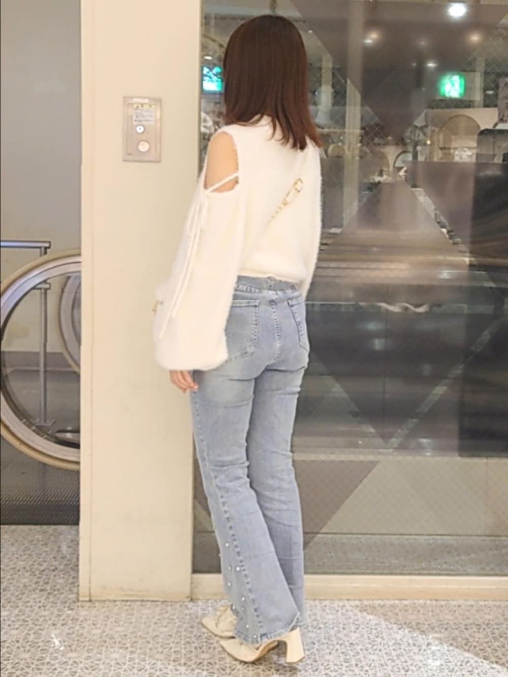 ホワイト系のニット/セーター、ホワイト系のショルダーバッグ、ブルー系のデニムパンツを着用したレディースの秋コーディネートの3枚目の写真