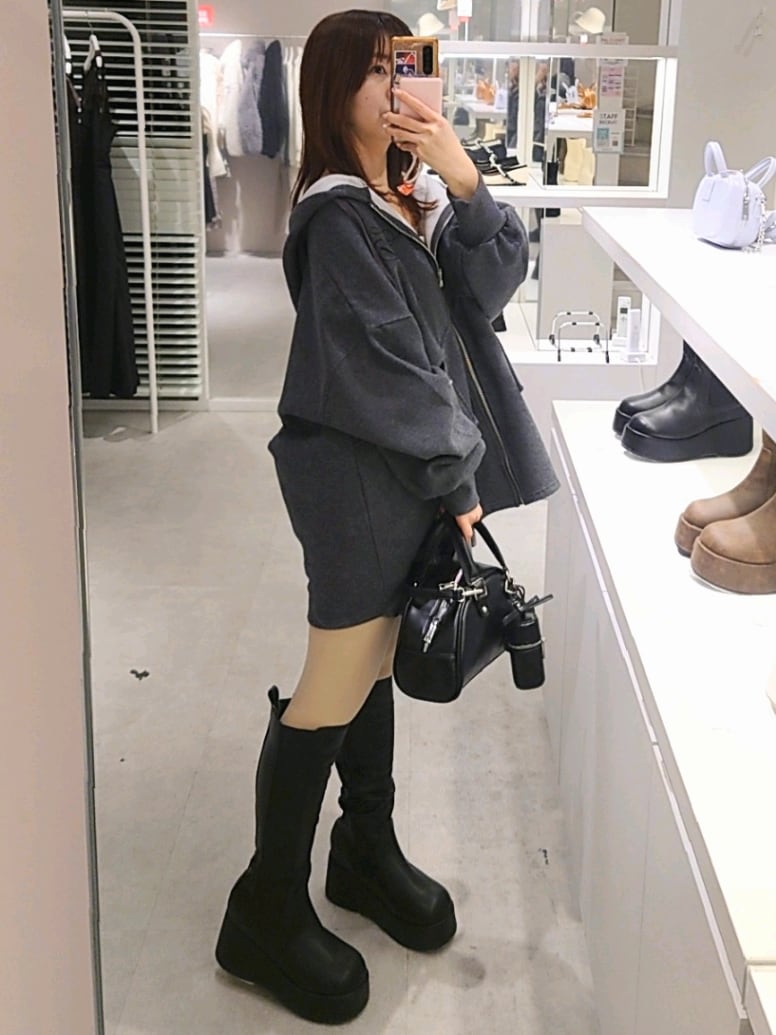 グレー系のパーカー、ホワイト系のキャミソール、グレー系のスカートを着用したレディースの冬コーディネートの4枚目の写真