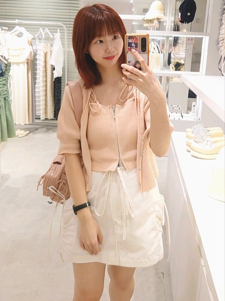 ピンク系のニット/セーター、ピンク系のショルダーバッグ、ホワイト系のスカートを着用したレディースの夏コーディネートの2枚目の写真