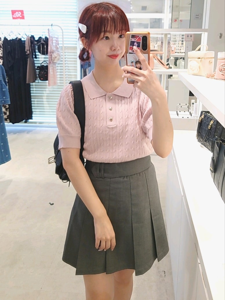 ピンク系のニット/セーター、グレー系のスカート、ブラック系のショルダーバッグを着用したレディースの夏コーディネートの2枚目の写真